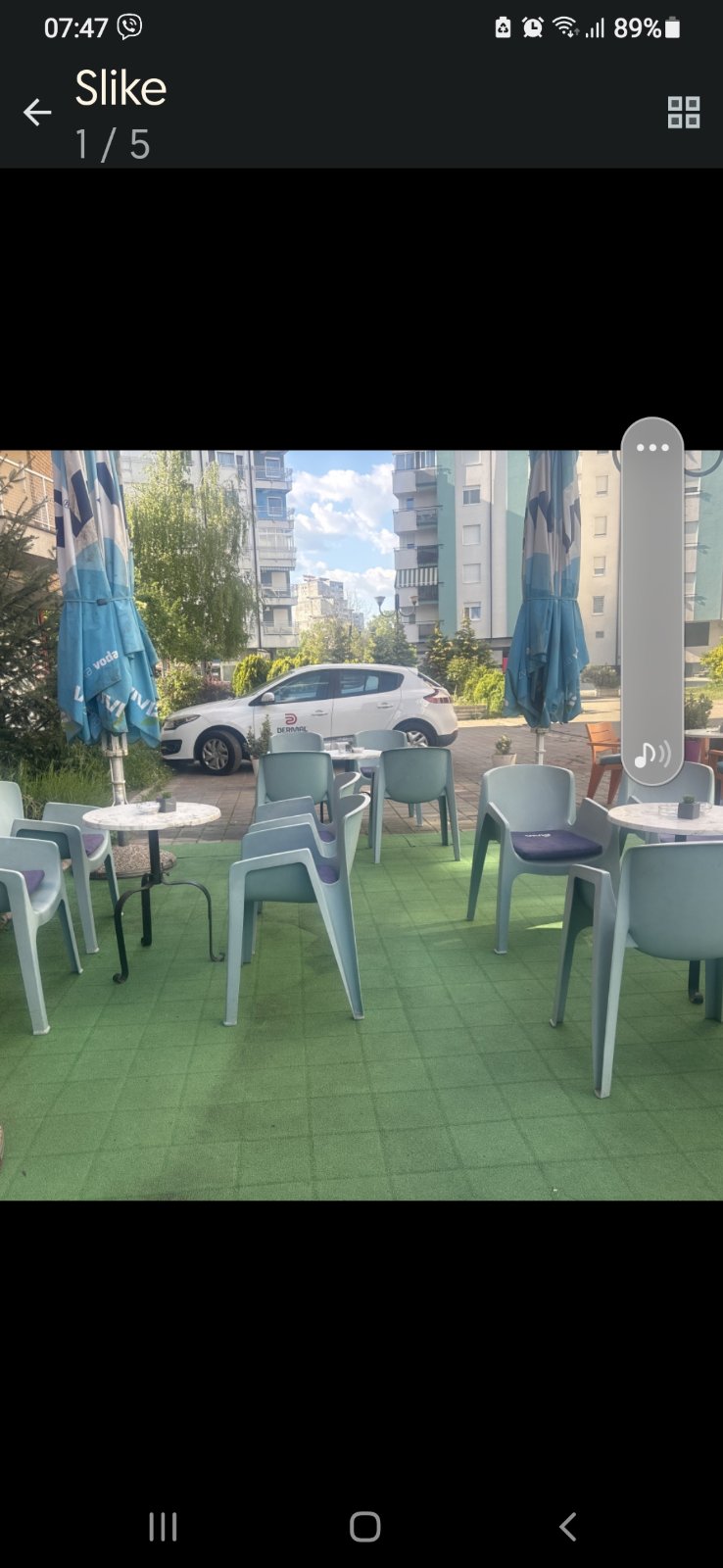 Terasa sa sivoplavim stolicama, sklopljenim plavim suncobranima i zelenim podom