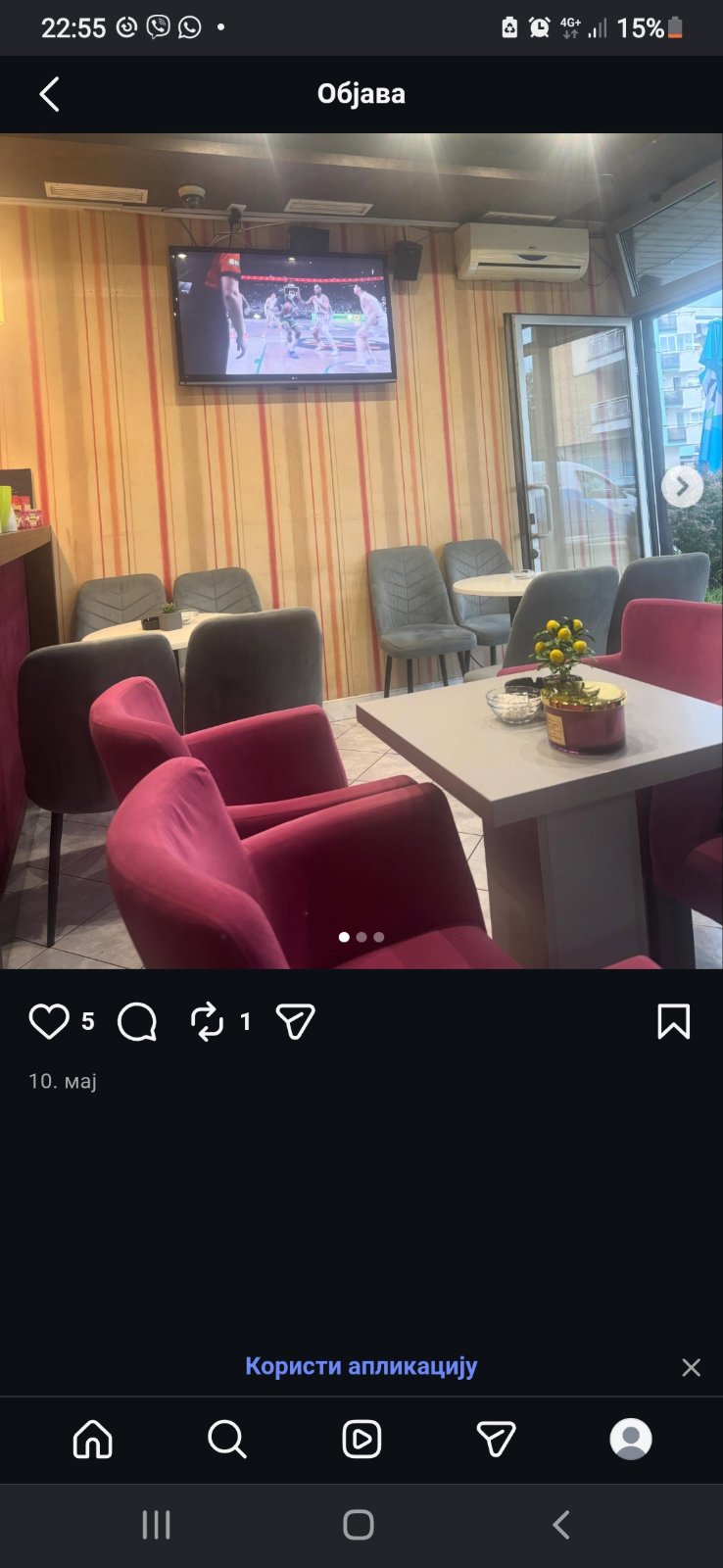 Fotelje boje ciklame i sive stolice ispred ekrana na kojem je sportski prenos